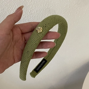 Detailed texture of olive green knitted headband with golden floral metal buckle detail