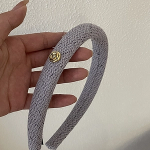 Detail of lavender tweed headband featuring a gold camellia flower charm and soft texture