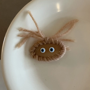 Macro della molletta per capelli fatta a mano in maglia marrone con occhi blu realistici