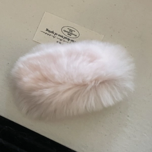 Détail de la texture douce en fausse fourrure rose clair sur une pince à cheveux pelucheuse