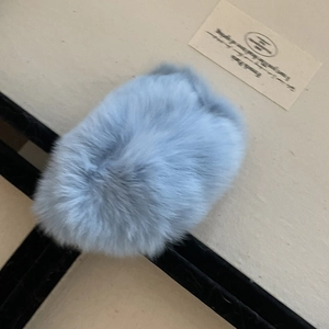 Détail d'une pince à cheveux en fausse fourrure bleu clair sur un fond minimaliste
