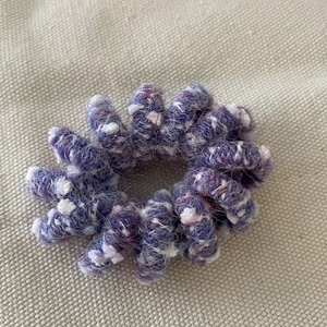 Detail of purple knitted wool wrap on elastic spiral hair tie with soft texture