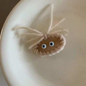 Fermaglio per capelli a mostro lavorato a maglia con occhi blu su piatto di ceramica