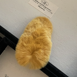 Détail d'une pince à cheveux en fausse fourrure jaune gingembre avec texture pelucheuse douce