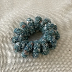 Macro shot of blue-green knit yarn texture on elastic spiral telephone wire hair tie