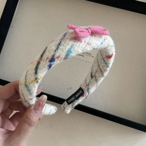 Detail of handmade knit headband with colorful spots and a pink bow decoration