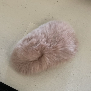 Vue détaillée d'une pince à cheveux en peluche rose doux sur fond textile beige