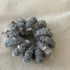 Macro detail of grey knitted hair tie with brown and beige speckled woolen texture