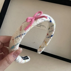 Detail of handmade knit headband with colorful polka dots and a magenta bow accent