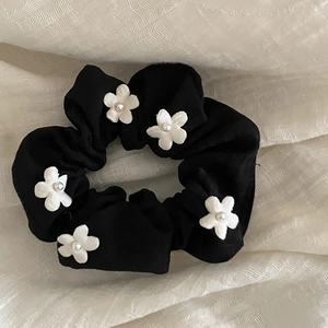 Detail of black pleated scrunchie with white floral embroidery and pearl centers