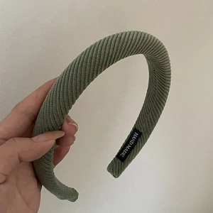 Detailed macro view of green corduroy headband featuring a white Hand Made textile label