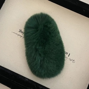 Pince à cheveux ovale en peluche vert foncé sur une carte artistique au ton neutre