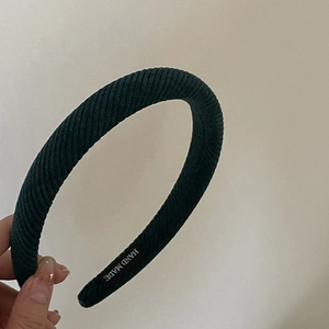 Deep green velvet headband with handmade label showing a high top wide padded design