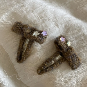 Close-up of handmade pumpkin orange knitted bow hair clips with small star decorations