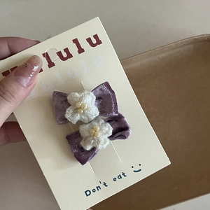 Detail of purple velvet bow hair clips with pearls and knit flowers on card