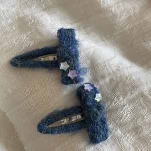 Close-up of blue knitted wool BB hair clips with matte purple and gray stars decoration