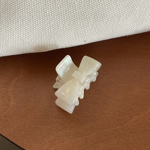 Close-up of a cream-white acetate bow hair claw clip with a natural pearl luster finish