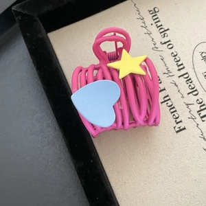 Pink heart and star hair claw clip with a hollow cage design on a beige textured background