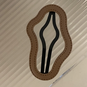 Close-up of a brown leather cloud-shaped hair clip with decorative stitching and wave edges