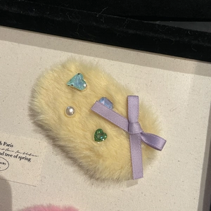 Détail d'une pince à cheveux jaune en fausse fourrure avec gemmes colorées et perle