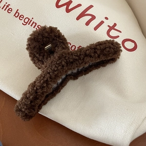 Détail de la grande pince à cheveux en peluche marron foncé avec texture douce en peau de mouton