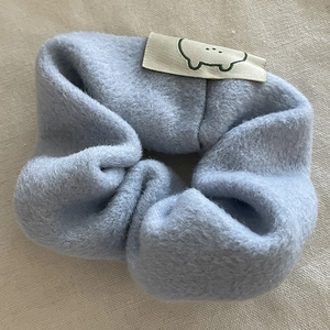 Détail d'un chouchou en peluche bleu clair avec patch d'ours sur texture polaire