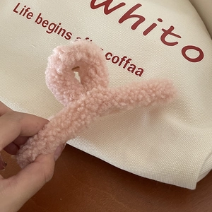 Détail d'une pince à cheveux rose en peluche douce type bouclée tenue en main