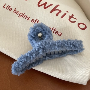Gros plan d'une pince à cheveux en peluche bleue avec ressort sur fond de toile de jute