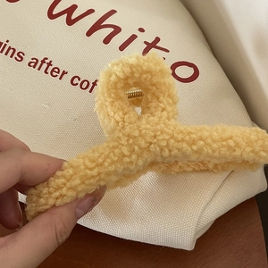 Gros plan sur la pince à cheveux en peluche jaune montrant la texture sherpa et le ressort
