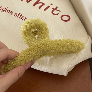 Détail de la pince à cheveux en peluche vert moutarde montrant la texture douce