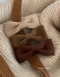 Detailed close-up of three velvet bow hair clips in beige and brown autumnal tones