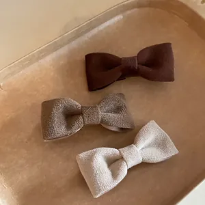 Three-piece velvet bow hair clips set in brown and beige tones on a textured background
