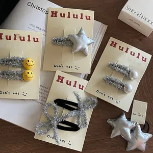 Glittery silver hair clip set with star and smiley designs on yellow display card