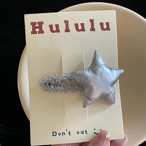 Close-up of a silver plush star-shaped hair clip for girls on a yellow card holder
