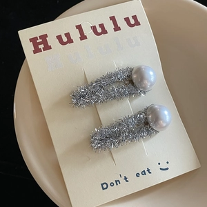 Detail of silver glitter hair clips with white pearls on a display card in a ceramic bowl