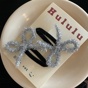 Close-up of cute silver glitter bow hair clips for girls on a white display card