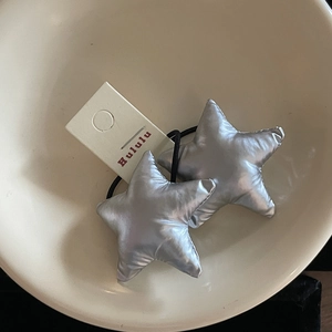 Silver star hair ties with metallic knit texture and black elastic bands in a white bowl