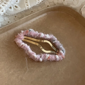 Détail macro de la barrette à cheveux tricotée en forme de nuage rose et gris