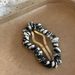 Détail d'une barrette à cheveux nuage en tricot noir et blanc avec base en métal doré