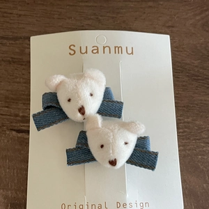 Detailed close-up of cute plush bear denim bow hair clips on a display card