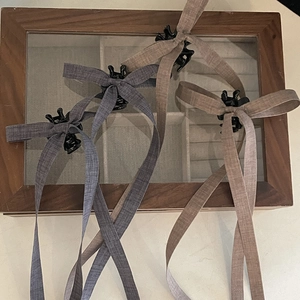 Three-piece brown bow hair clips with long ribbons displayed on a wooden jewelry box