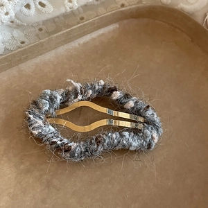 Détail de la pince à cheveux en tricot duveteux avec base en métal doré ondulé