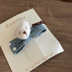 Detail of denim bow hair clip featuring a plush bear head and silver star accents