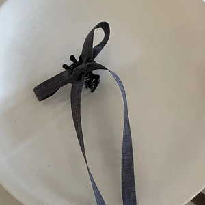 Deep gray bow hair claw clip with long ribbons and elegant matte fabric texture