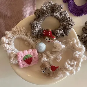 Handmade crochet hair scrunchies with cute doll charms on a white ceramic plate