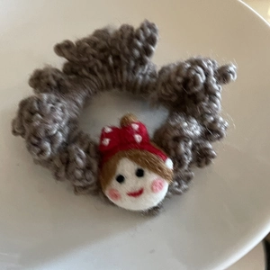 Detail of grey knitted hair tie with cute wool felt doll head and polka dot bow