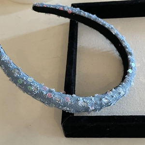 Detail view of light blue denim headband with colorful sequins and black velvet lining