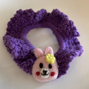 Detailed macro view of handmade purple crochet hair tie with a pink felt doll decoration