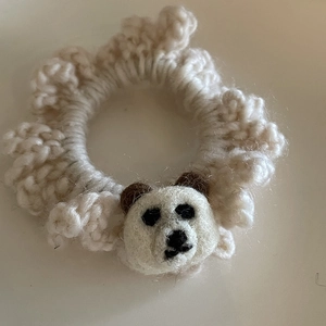 Close-up of handmade cream crochet hair tie with a cute knitted brown bear mascot