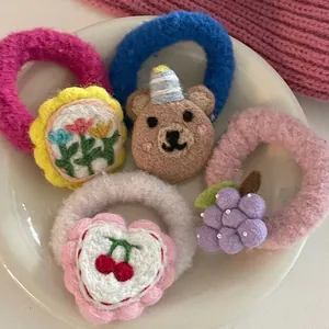 Detailed close-up of wool felt hair ties with cartoon bear and fruit embroidery
